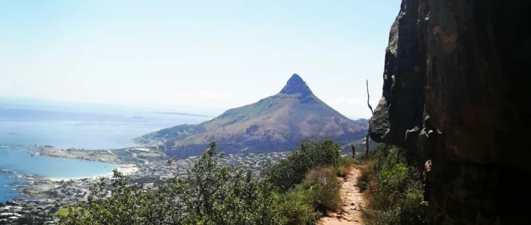Narrow dirt trail winding along a rocky mountainside towards Lion's Head, Cape Town, below
