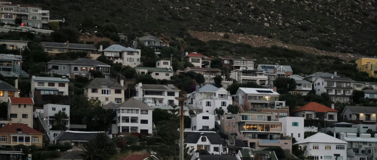 Whitewashed houses on a hillside at Fish Hoek at dusk with a pink evening sky above the mountain