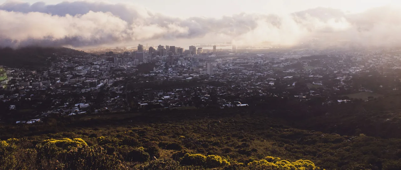 Cape Town's city bowl at sunrise, cloud and mist rolling over the mountain behind the buildings