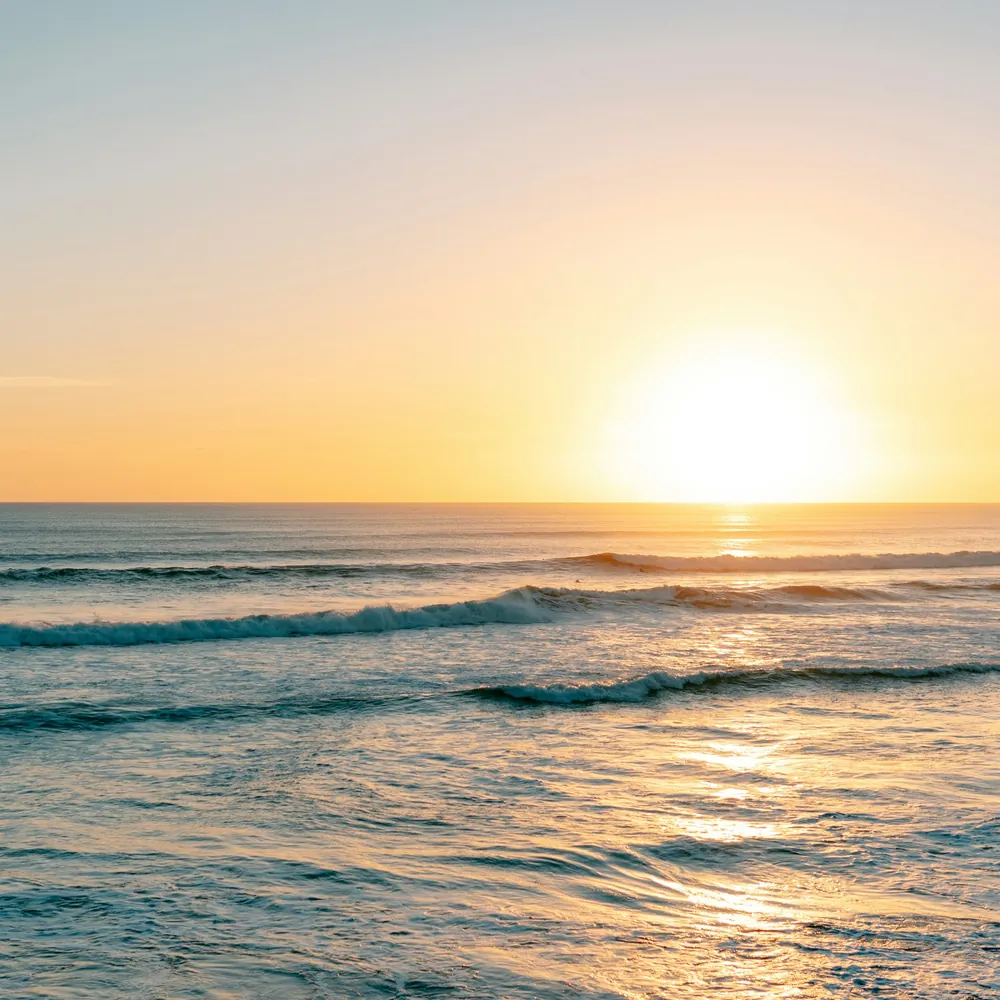 Calm sea waves under a pale sky at sunrise