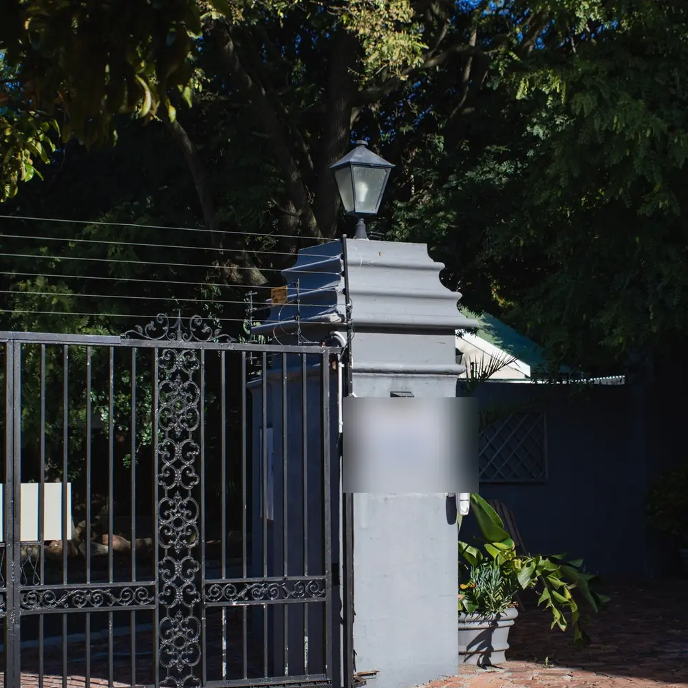 The centre's gated driveway entrance under tall trees, with a lantern on the stone pillar