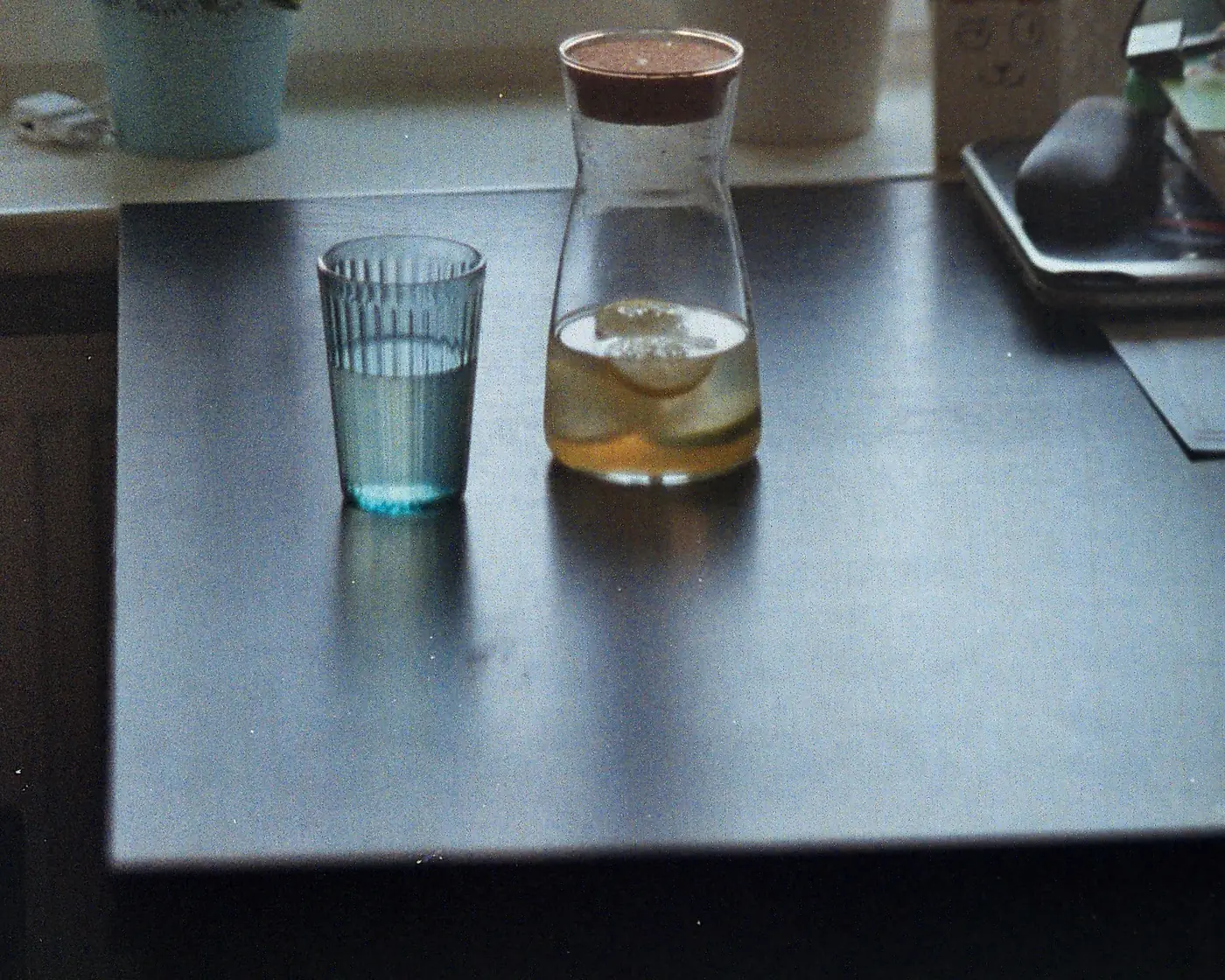 A glass and jug of water on a table by a sunlit window
