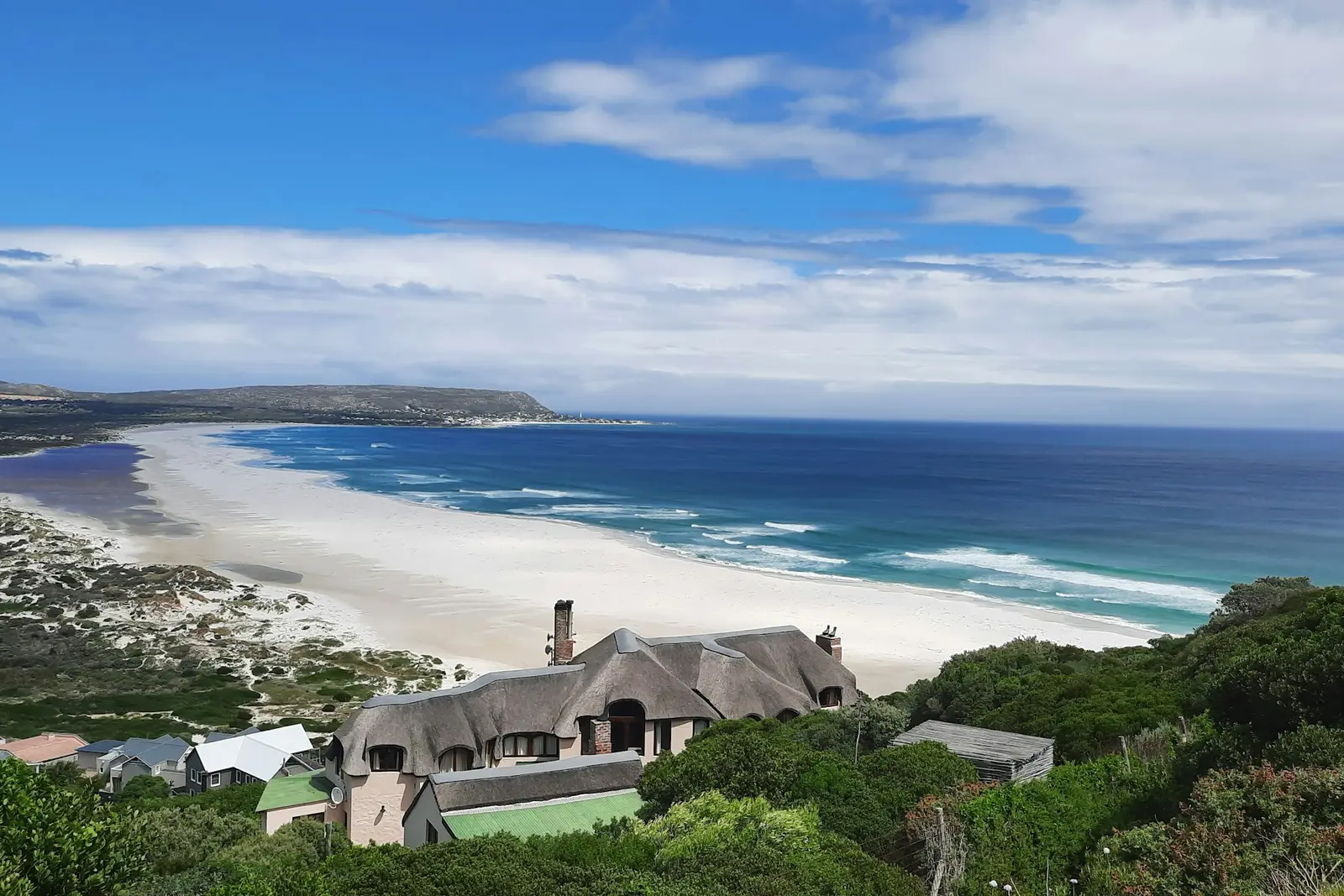 A thatched house above a long, empty beach on the Cape Peninsula