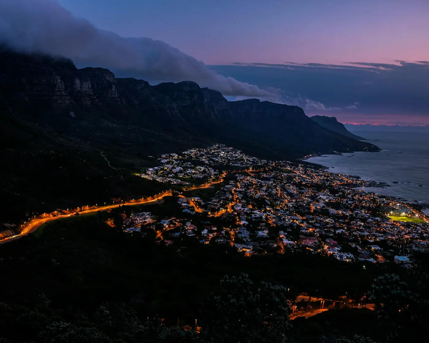 Lion's Head at dusk above the lit-up streets of Camps Bay, Cape Town