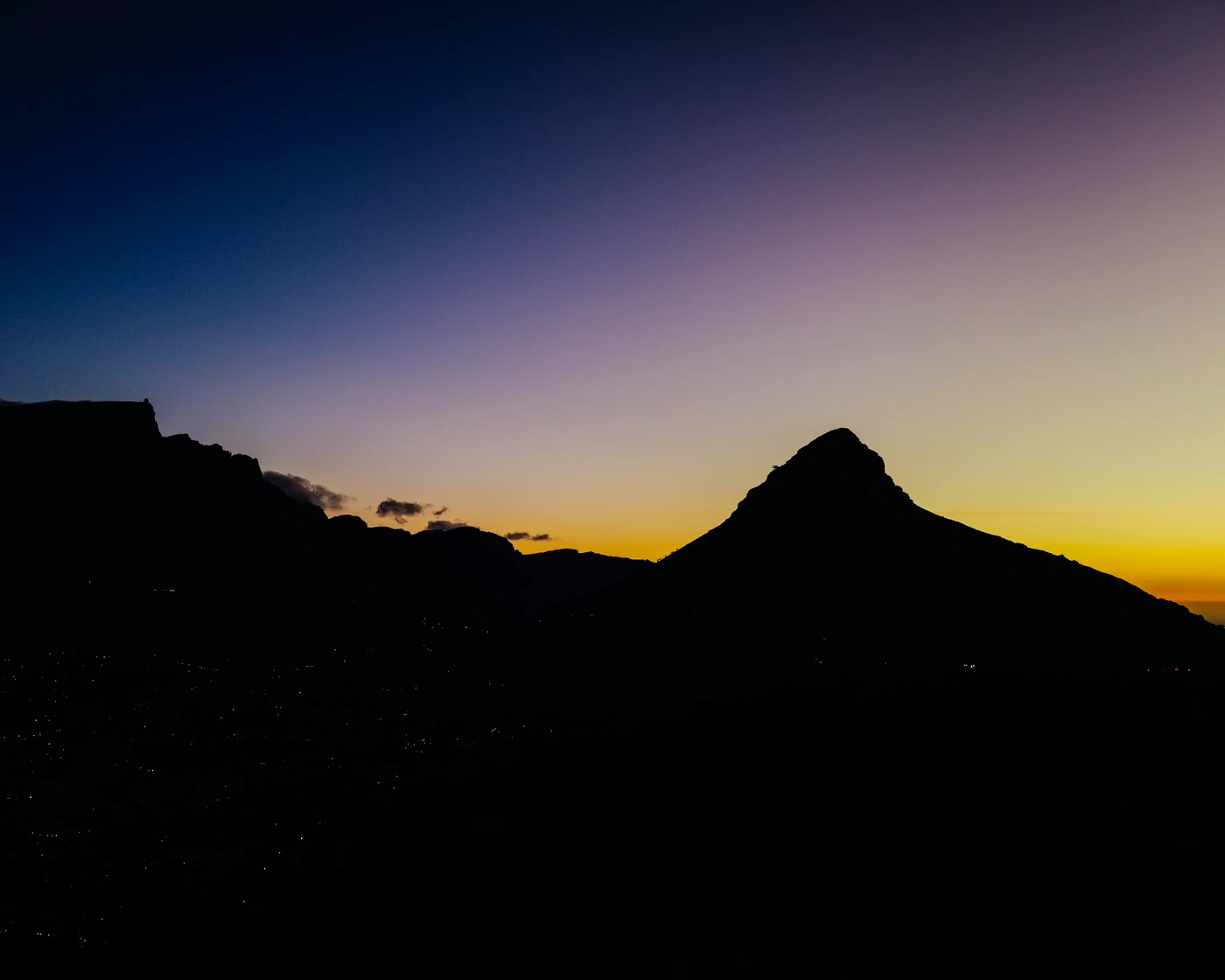 Lion's Head silhouetted against a deep blue and gold dusk sky over Cape Town