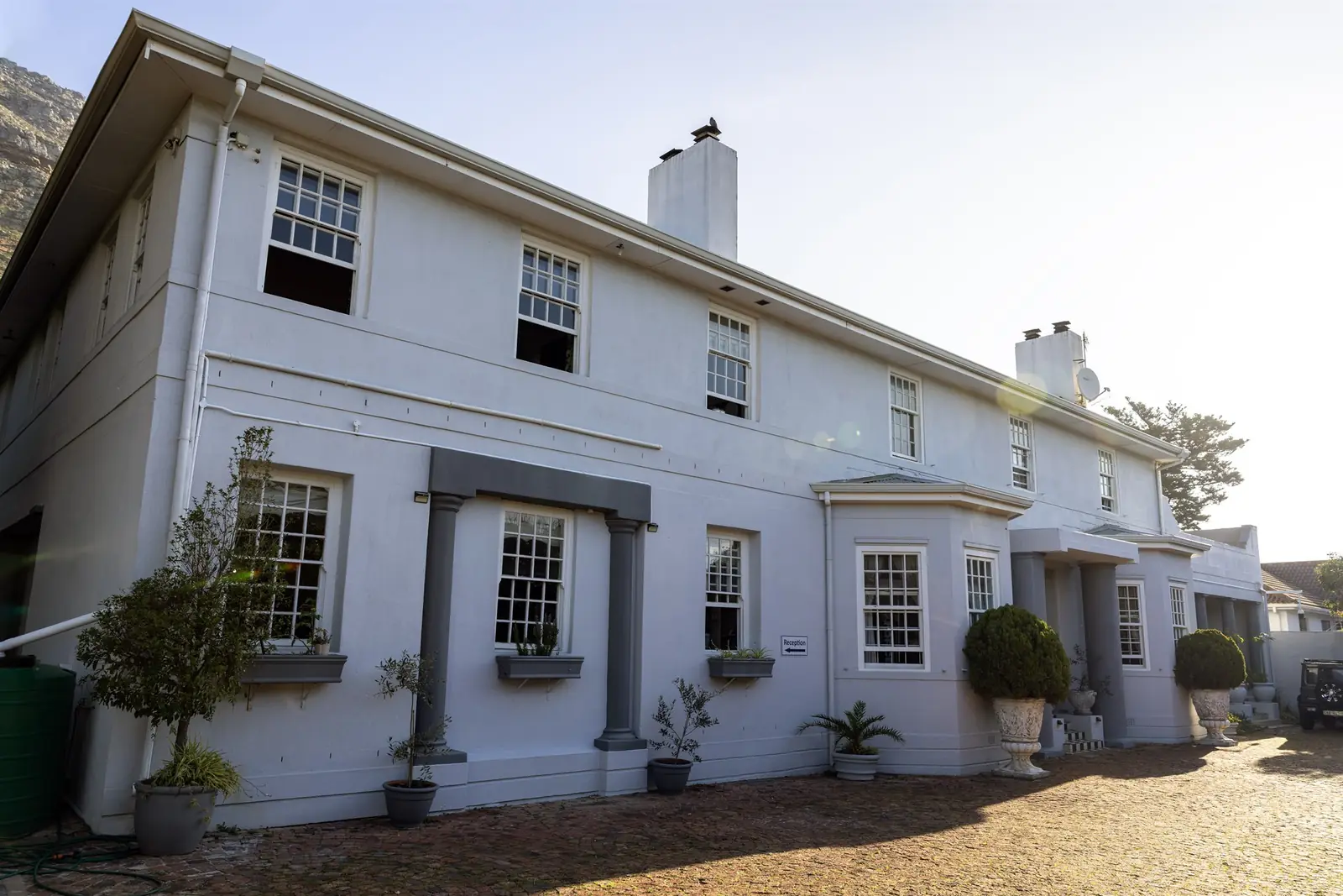 The white two-storey main house of the centre, with potted olive trees along the front