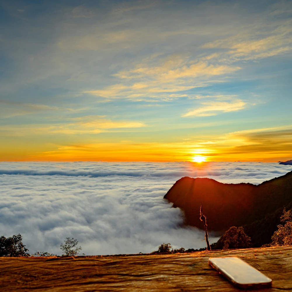 Sun rising over a sea of clouds with a golden and blue sky