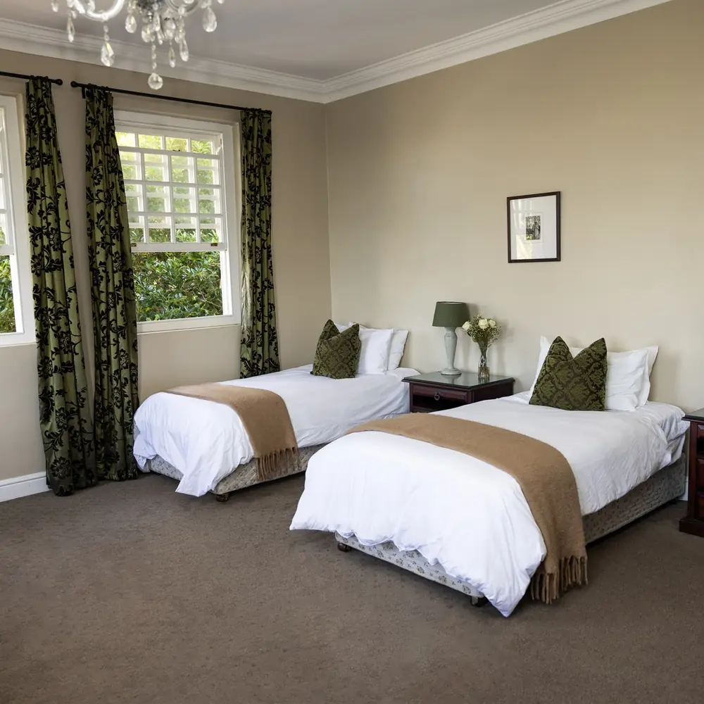 A bright twin bedroom at the centre, with made beds and a garden view