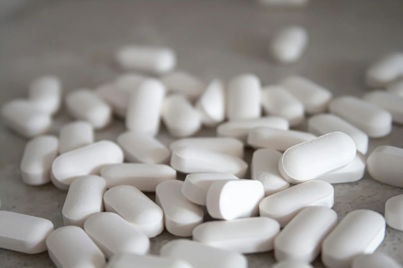 White oval tablets scattered on a pale grey surface