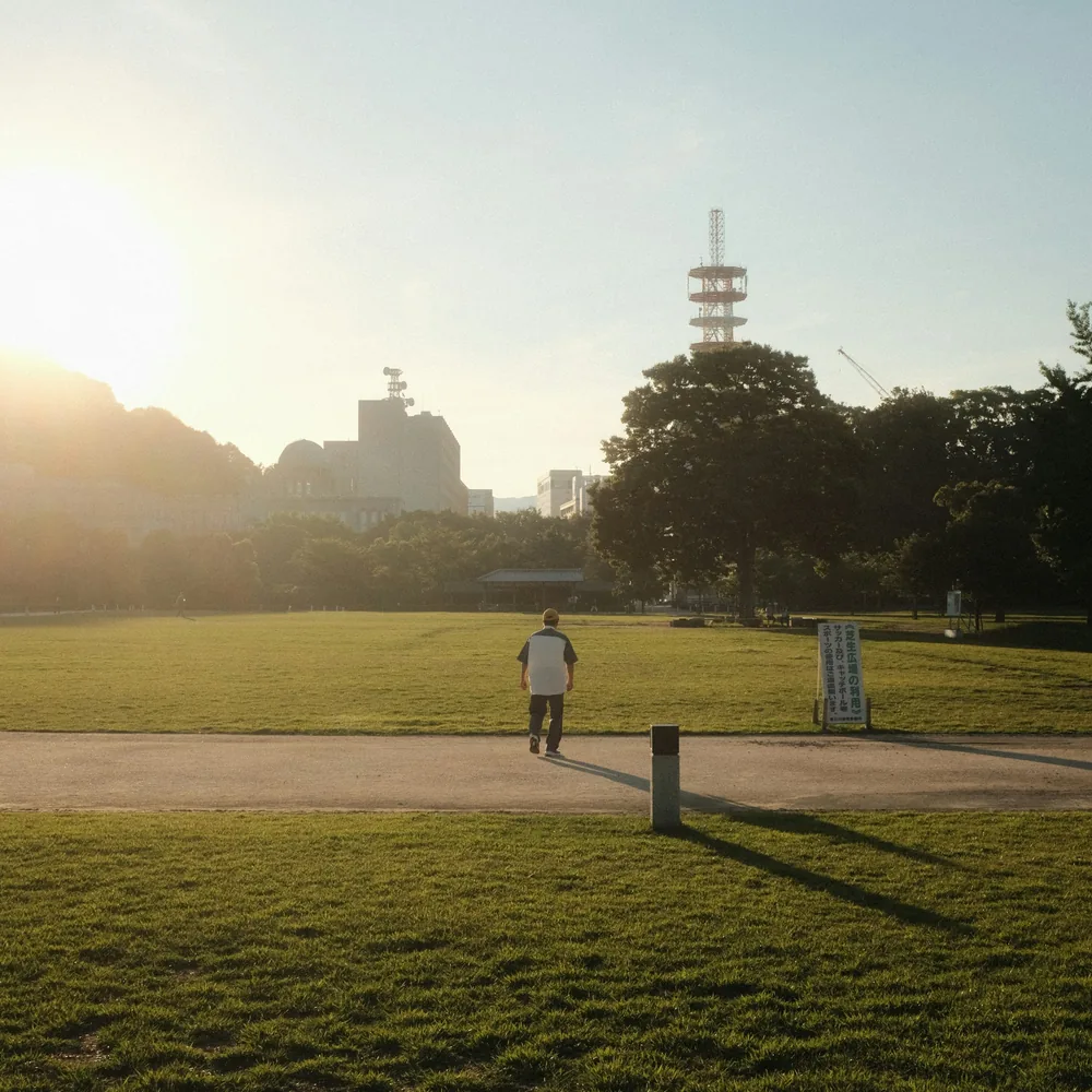 Sunlit park path with a lone walker in the distance and warm morning light