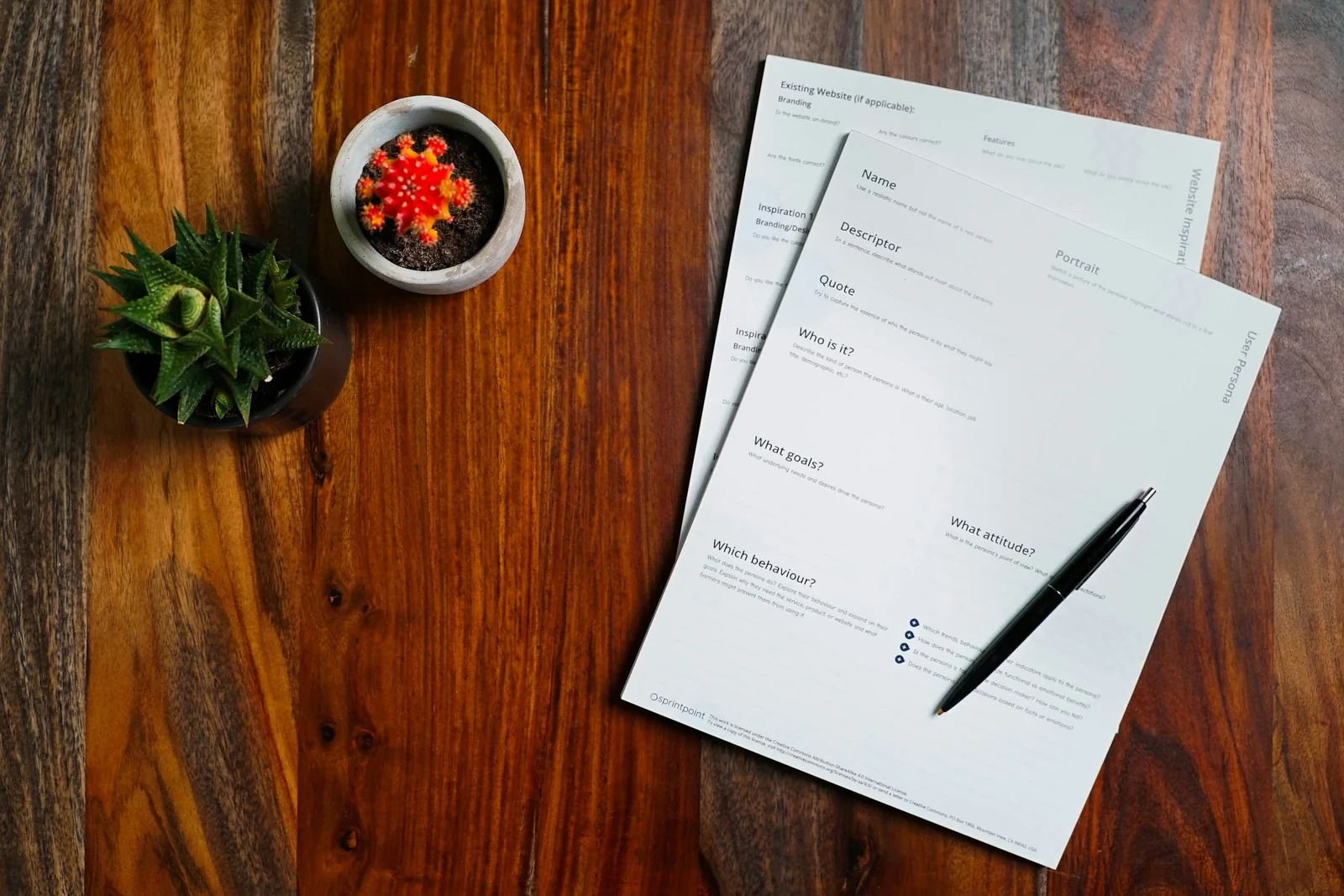 Printed questionnaire sheets with a black pen on a wooden table seen from above