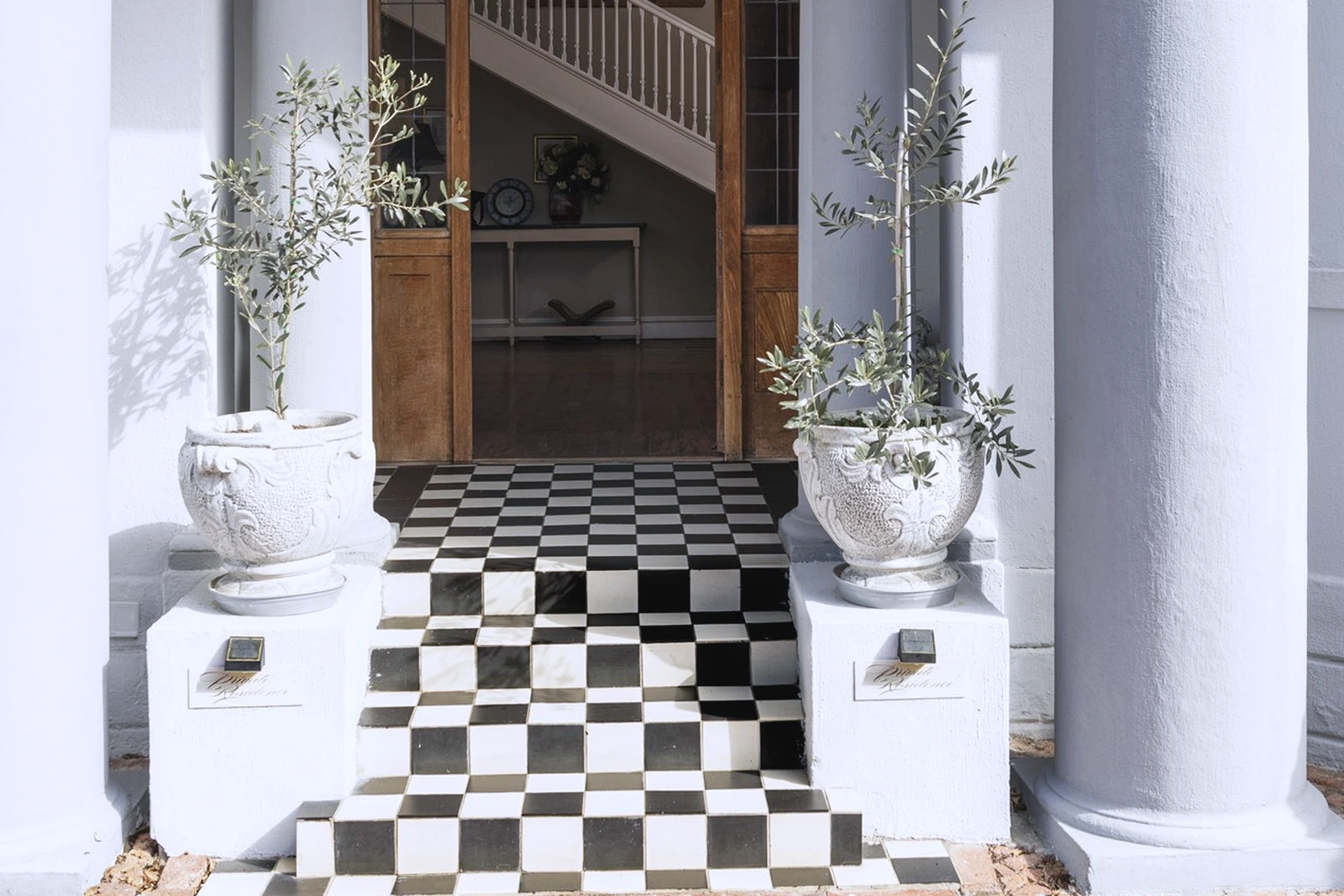 Black and white checkerboard tiled steps leading through an open door to a staircase in a Cape manor