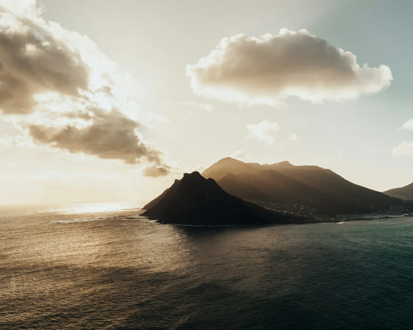 Hout Bay mountains in hazy golden light above dark water, Cape Peninsula