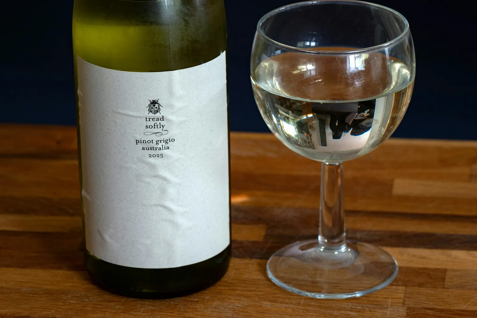 Bottle of white wine with a filled wine glass on a wooden counter