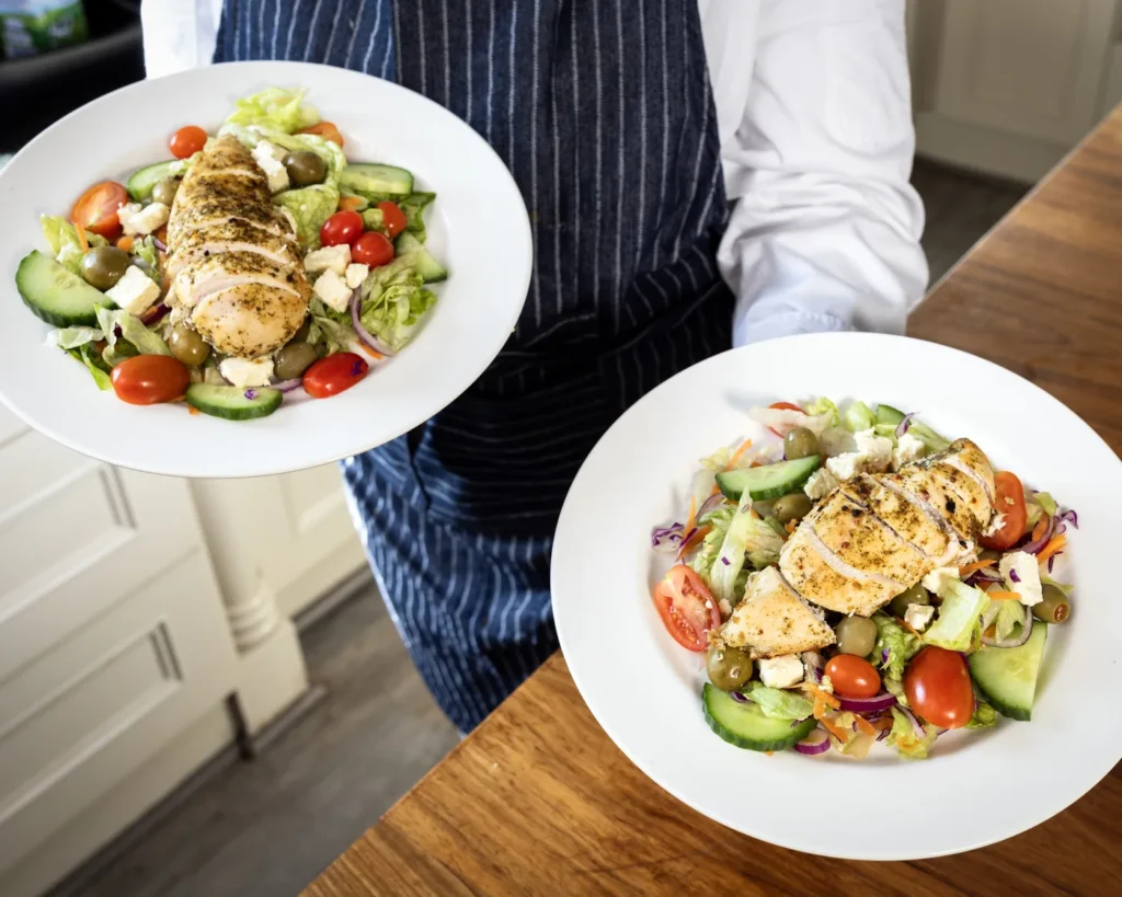 A chef serving two plates of fresh chicken salad at Renewed Life Center