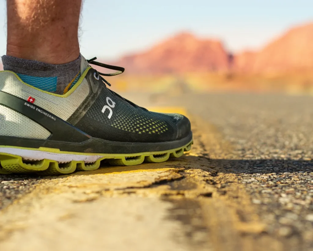 Running shoes standing on a road beside a yellow line in bright daylight
