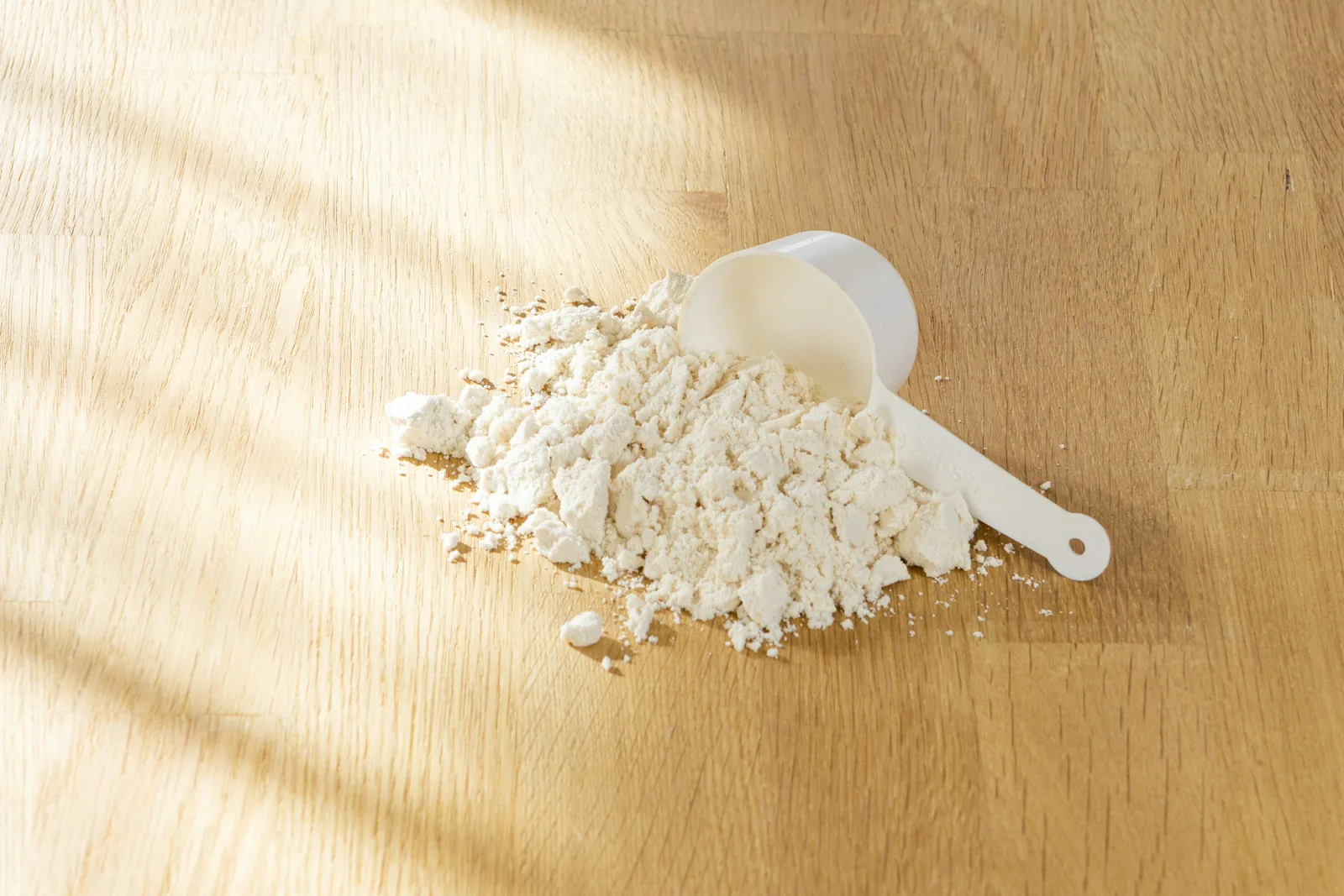 Pile of pale powder with a scoop on a wooden table in soft light