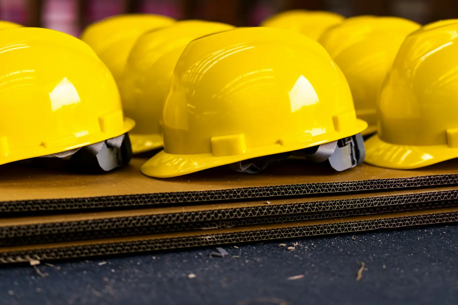 A row of yellow hard hats lined up on a work surface